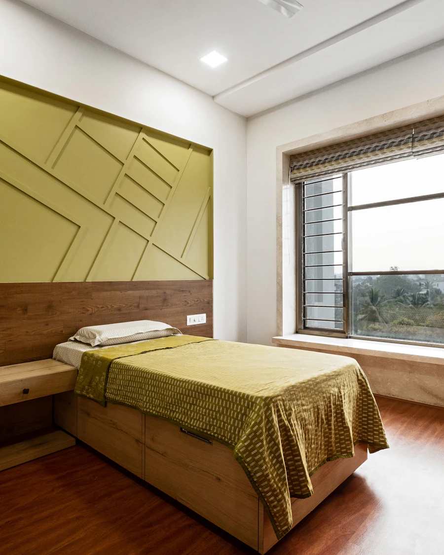 Bedroom interior with a panelled headboard wall and a louvred window over greenery