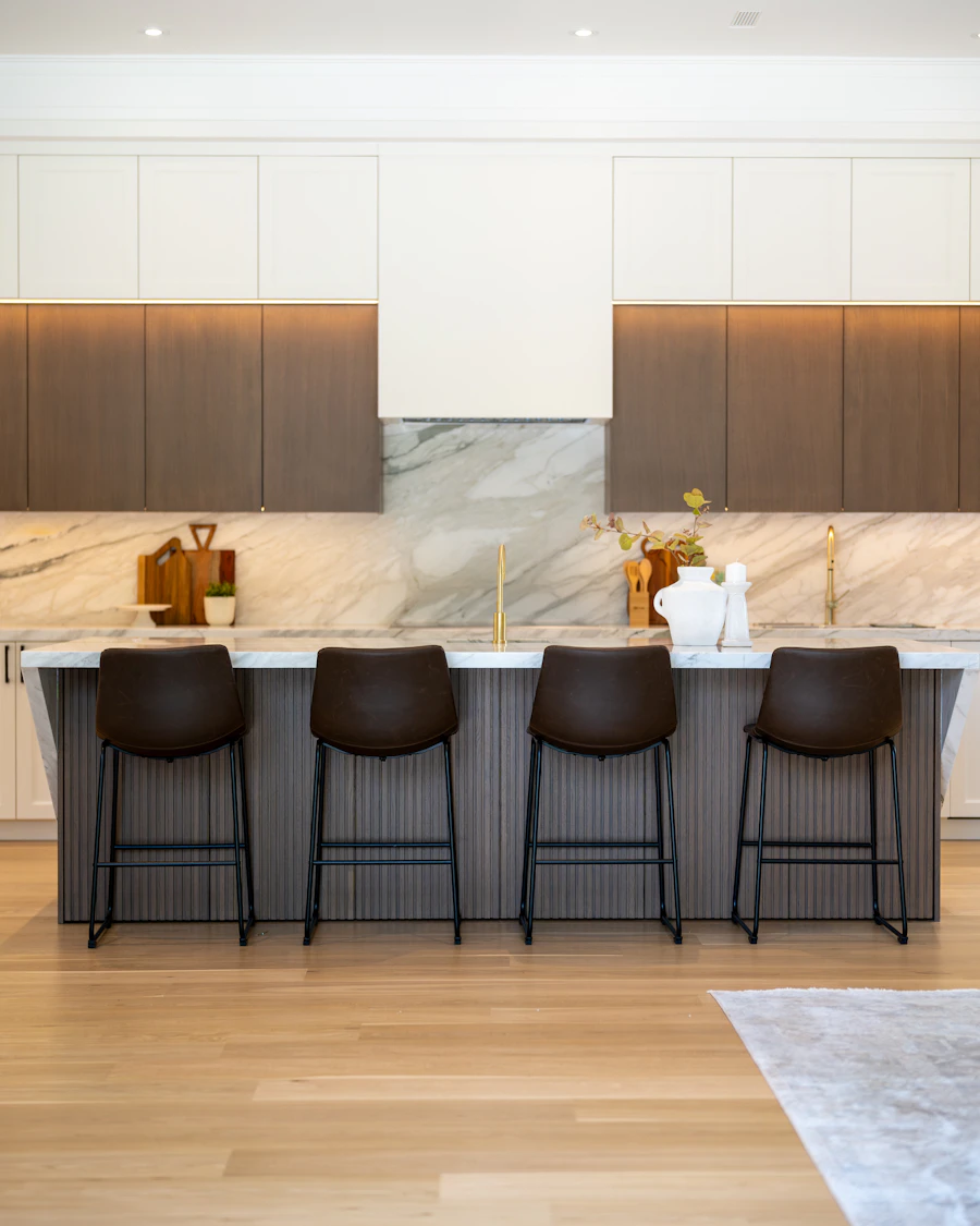 Modular kitchen island in engineered quartz with counter stools and pendant lighting