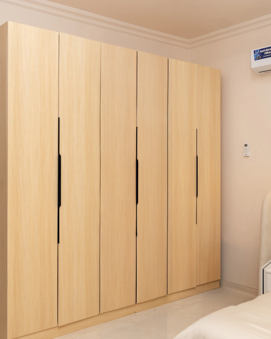 Full-height fitted wardrobe in marine ply with a pale wood finish along a bedroom wall